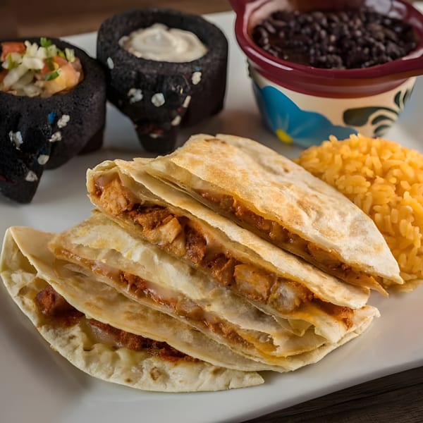 Chicken quesadillas with rice, black beans, pico de gallo, and sour cream on a white plate.