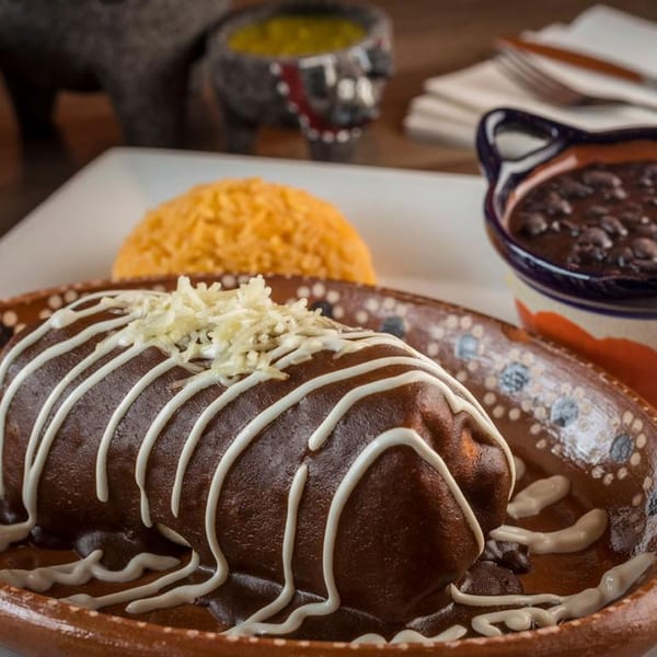 A mole enchilada with crema and cheese, served with rice and black beans.