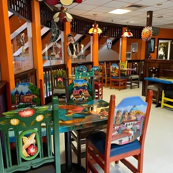 Vibrant Mexico City Taqueria dining room with colorful hand-painted chairs and tables, and festive decor.