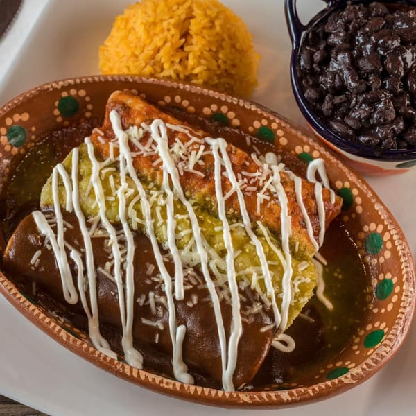 Mexico City Taqueria's enchiladas with red and green sauce, rice, and black beans in a decorative bowl.