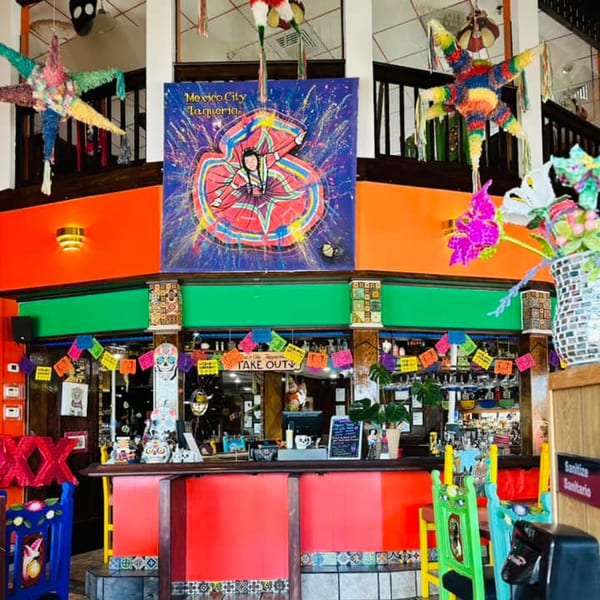 Vibrant interior of Mexico City Taqueria with colorful decor, piñatas, and a bar area.